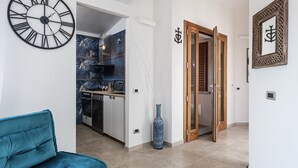 A modern kitchen with a clock, a blue sofa, and a wooden door. - Villa 'Iris' with Private Pool, Wi-Fi and Air Conditioning (Costa Rei)