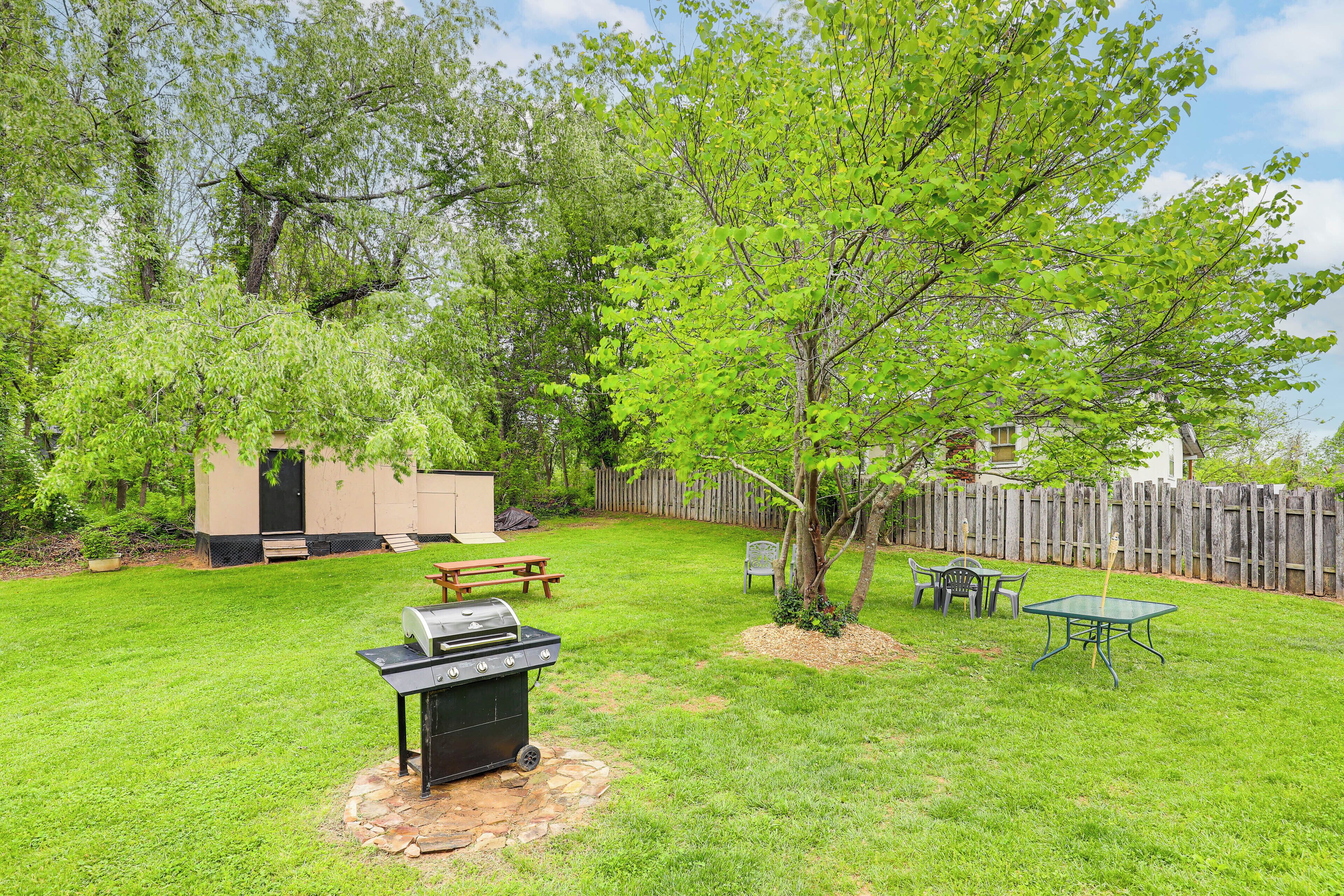 A backyard with a grill, picnic table, and a small shed.