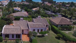 Zona residencial amb cases, un jardí i vistes al mar.