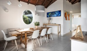 A dining area with a wooden table, white chairs, a potted plant, and a view through a window. - Villa 'Quattro' with Sea View, Wi-Fi and Air Conditioning (Costa Rei)