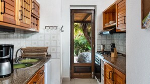 Uma cozinha compacta com armários de madeira, pia, fogão e cafeteira.