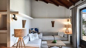 Uma sala de estar moderna com um sofá, uma mesa de centro e duas luminárias fixadas na parede.