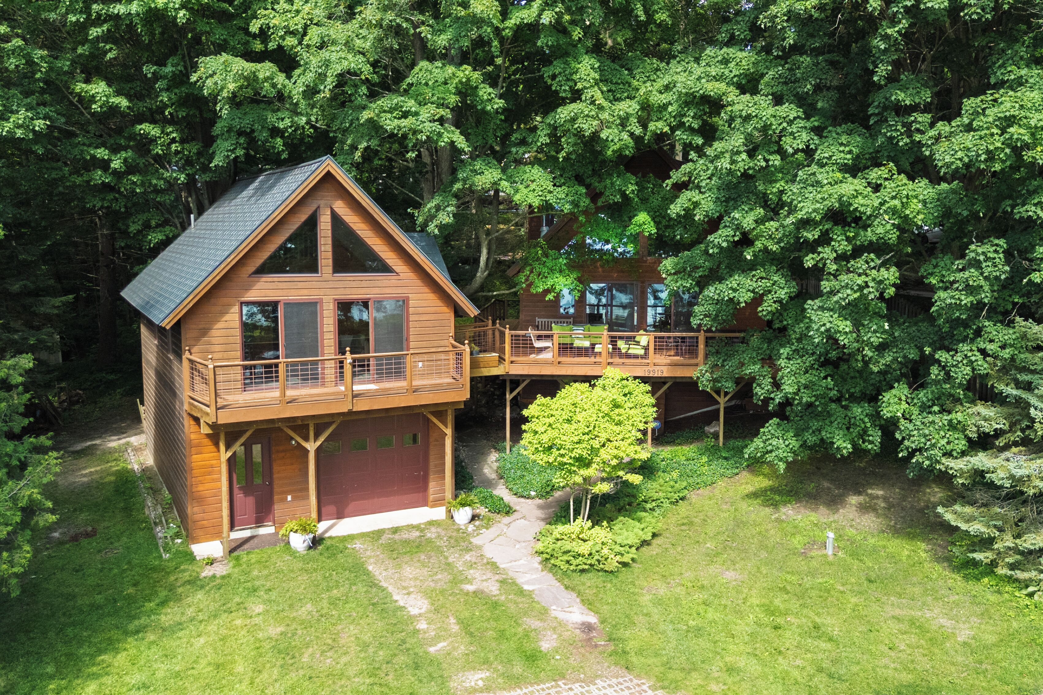 Une cabane en bois dotée d’un balcon et d’une terrasse, entourée d’une forêt dense.