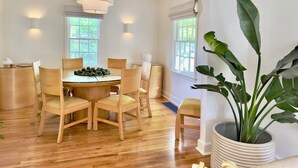 Un comedor con una mesa redonda, sillas de madera y una planta en maceta.