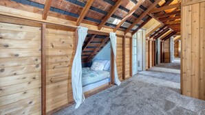 A wooden interior with a sloped ceiling, a bed with a canopy, and a carpeted floor. - Maxwelton Aerie Bluffside Retreat w/ Sweeping Puget Sound Views + Firepit (Clinton)