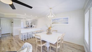 A spacious dining area with a white table, wooden chairs, and a decorative centerpiece. - 2 Condos, Steps to the Beach Pool+hot Tub, Balcony Lounge Triton & Sea Haven (Santa Rosa Beach)