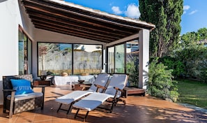 An outdoor patio with a pergola, seating area, and a view of the backyard.