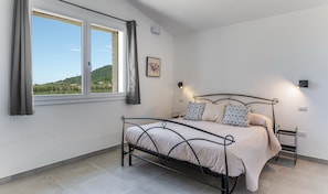 Une chambre à coucher avec un lit, une fenêtre, un tableau au mur et une table de chevet.
