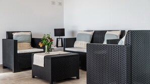 A room with a black wicker sofa set, a small table with a vase of flowers, and a lamp. - Villa 'Laccus 6' with Sea View, Wi-Fi and Air Conditioning (Castiadas)