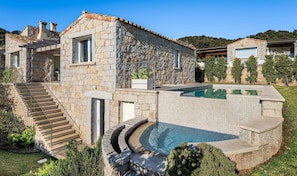 Une maison en pierre avec une piscine, un escalier et un jardin.