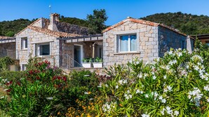A stone house with a tiled roof, a balcony, and a garden with various plants and flowers. - Villa 'Laccus 6' with Sea View, Wi-Fi and Air Conditioning (Castiadas)