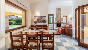 Un comedor con una mesa y sillas de madera, chimenea y vistas al exterior.