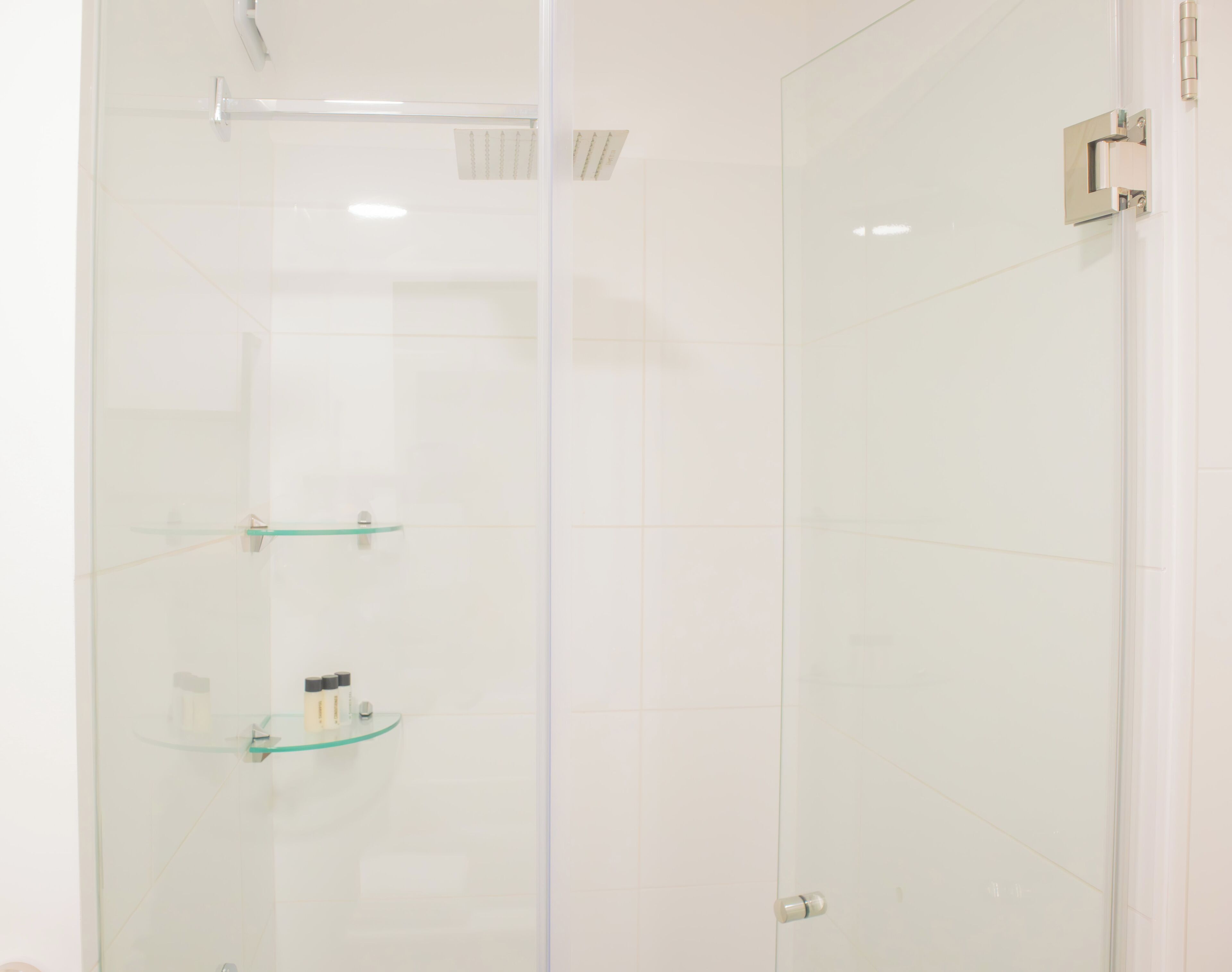 Eine gläserne Dusche mit Ablage für Toilettenartikel.