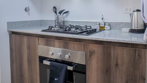 Une cuisine moderne équipée d’une cuisinière à gaz, d’un four et d’appareils électroménagers en acier inoxydable.