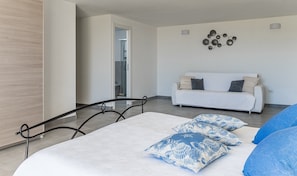 A modern bedroom with a bed, a sofa, and a decorative wall piece.