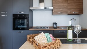 Eine moderne Küche mit Einbauofen, Gasherd, Kaffeemaschine und einer Weinflasche.