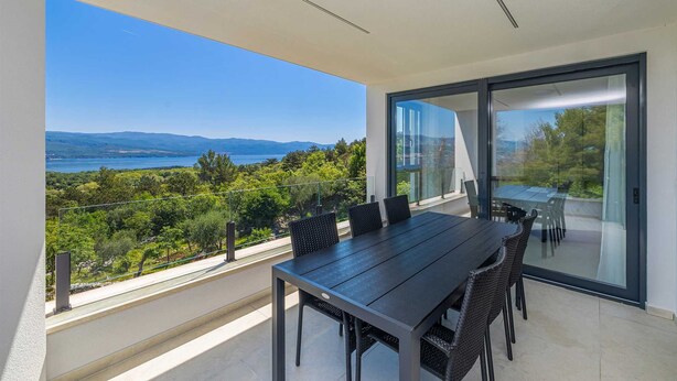 A balcony with a dining table and chairs, a glass door, and a view of a lake and mountains. - Apartment SEASIDE II with panoramic seaview (Polje)