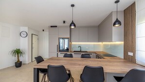 A modern kitchen with a central island, black chairs, pendant lights, and a potted plant. - Apartment SEASIDE II with panoramic seaview (Polje)