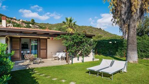 Una casa con patio, muebles de exterior y vistas a una colina.