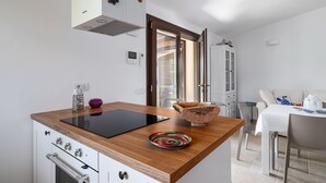 Una cocina moderna con encimera de madera, estufa integrada y un comedor con mesa y sillas.