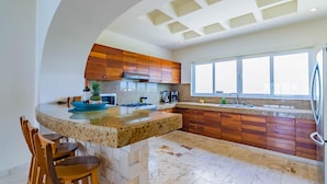 A modern kitchen with a central island, wooden cabinets, and a large window providing natural light.