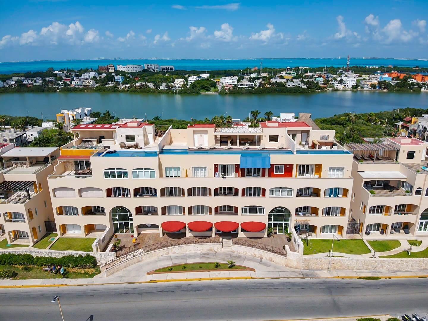 A multi-story hotel with balconies, a swimming pool, and a view of the ocean.