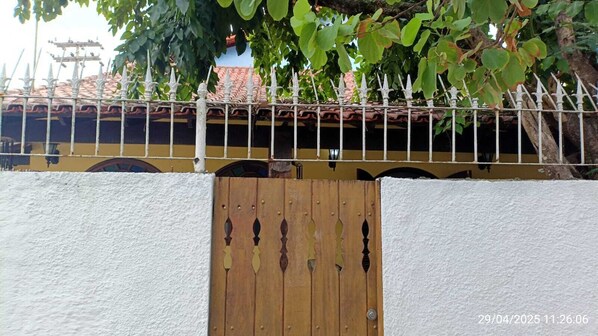 Une entrée fermée par un portail en bois et un mur blanc.