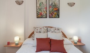 A bed with floral bedding, two nightstands with lamps, and two wall-mounted lamps. - Villa 'Sofia' with Private Pool, Wi-Fi and Air Conditioning (Costa Rei)