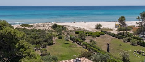 A coastal property with a beach, green lawns, and a tiled roof.