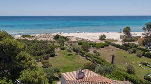 A coastal property with a beach, green lawns, and a tiled roof.