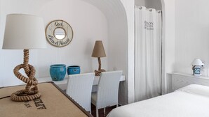 A room with a bed, a desk with two chairs, a lamp, a wall clock, and a mirror. - Villa 'Casa 14' with Sea View, Private Terrace and Air Conditioning (Castiadas)
