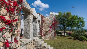 A stone building with steps leading up to a white door, surrounded by red flowers and a clear sky. - Villa 'Casa 14' with Sea View, Private Terrace and Air Conditioning (Castiadas)
