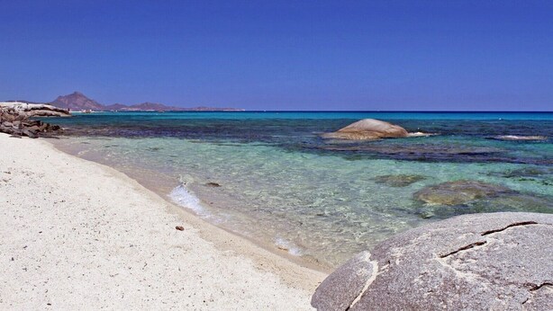 A beach with clear water, a large rock in the foreground, and a mountain in the background. - Villa 'Casa 14' with Sea View, Private Terrace and Air Conditioning (Castiadas)