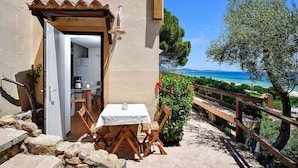 Una terrazza esterna con tavolo e sedie, una panca di legno e vista sul mare.