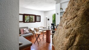 Un interno moderno con zona pranzo, divano e una grande parete rocciosa.
