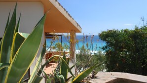 A building with a balcony overlooking the sea, surrounded by plants. - Villa 'Nido 3' with Sea View, Wi-Fi and Air Conditioning (Costa Rei)