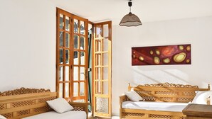 A room with two wooden beds, a large open window, and a hanging pendant light. - Villa 'Massidda' with Sea View, Wi-Fi, and Air Conditioning (S.Margherita di Pula)