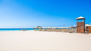 A beach with a wooden structure, umbrellas, and beach chairs. - Villa 'Massidda' with Sea View, Wi-Fi, and Air Conditioning (S.Margherita di Pula)