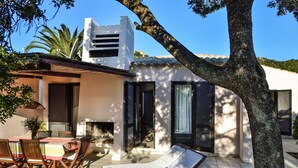 A house with a patio, a dining area with chairs and a table, and a lounge chair. - Villa 'Villetta 9' with Private Terrace, Wi-Fi and Air Conditioning (Costa Rei)