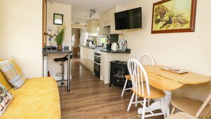 Une cuisine chaleureuse avec un coin repas, un plancher en bois et un téléviseur fixé au-dessus du comptoir.
