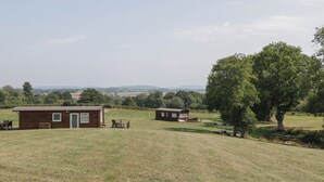 Une cabane rustique avec une façade en bois, une petite véranda et une vue sur la campagne environnante.