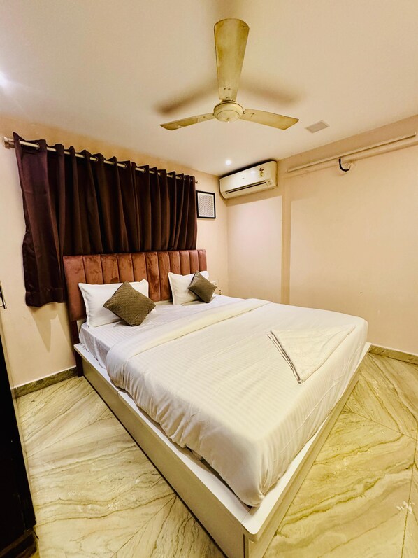 A neatly made bed with a headboard, a ceiling fan, and an air conditioning unit on the wall.