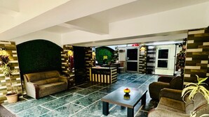 A spacious lobby with a reception desk, seating area, and a decorative wall.
