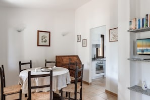 Uma sala de jantar com uma mesa redonda, cadeiras e um armário de madeira.
