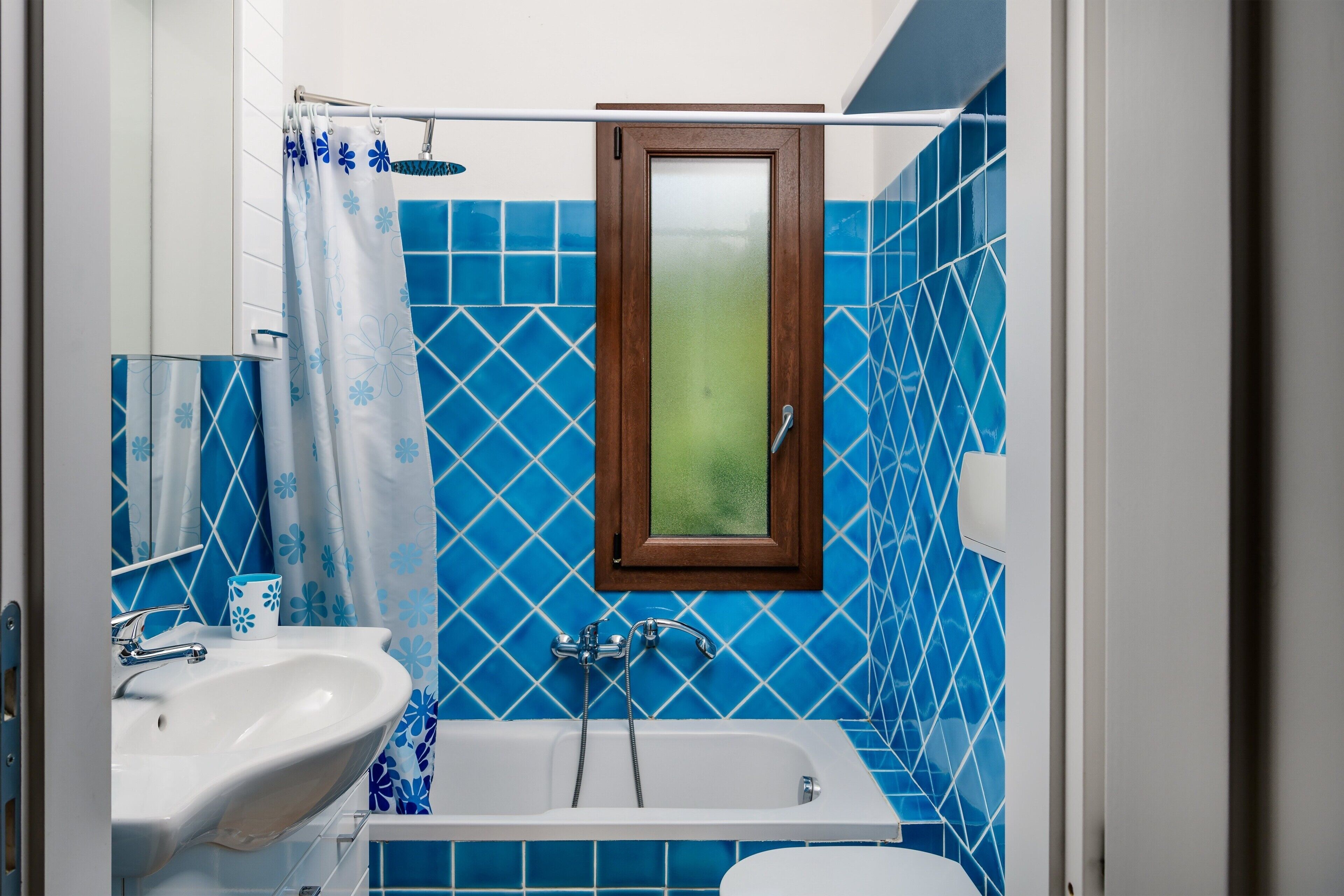 A bathroom with a white sink, a bathtub, and a shower curtain with a floral pattern.
