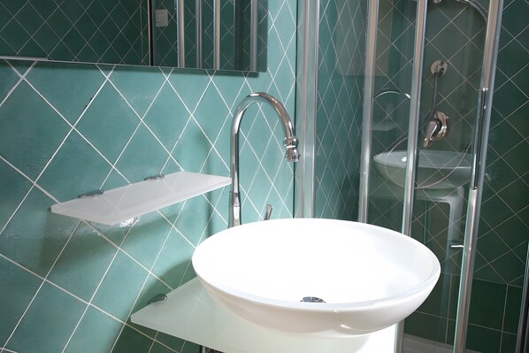 A bathroom with a white sink, a mirror, and a shower enclosure.