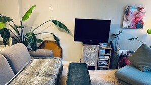 A living room with a sofa, a coffee table, a TV, and a bookshelf.