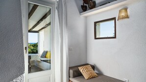 A room with a bed, a window with a view, a door, and a small table with a chair. - Villa 'Villetta 3' with Sea View, Wi-Fi and Air Conditioning (Costa Rei)