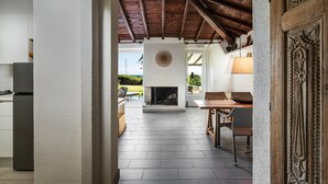 A modern kitchen with a built-in refrigerator, a fireplace, and a dining area with a table and chairs. - Villa 'Villetta 3' with Sea View, Wi-Fi and Air Conditioning (Costa Rei)