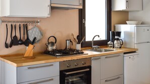 Une cuisine de taille réduite, équipée d’une cuisinière à gaz, d’un four, d’un évier et de meubles blancs.